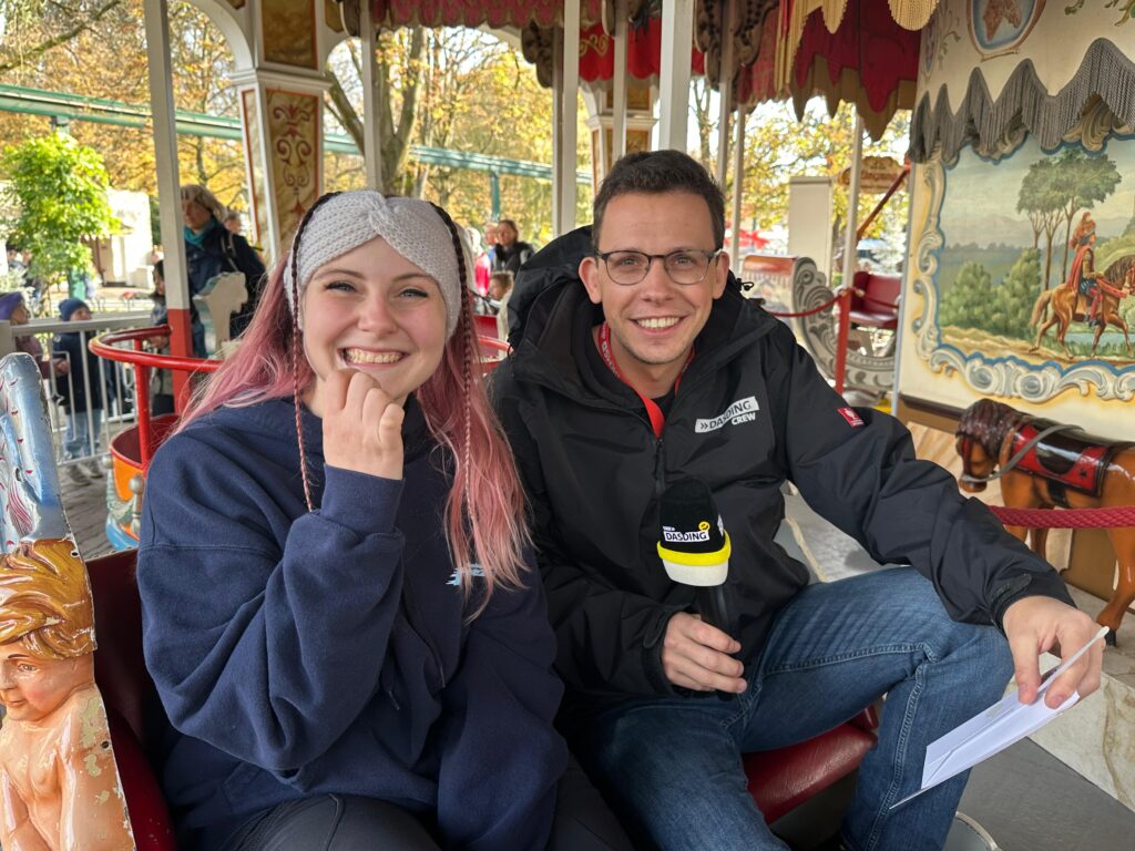 Besucherin Maxi zeigt mit DASDING Reporter Marco, dass eine Typisierung auch im über 100 Jahre alten "The British Carousel" im Europa-Park ganz einfach ist © Europa-Park GmbH & Co Mack KG